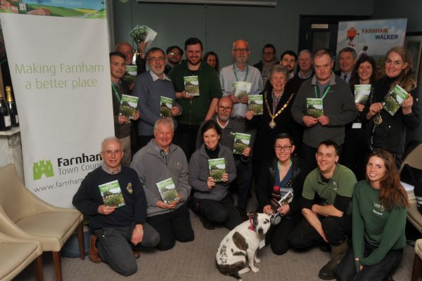 Group of people holding a booklet. Dog in foreground