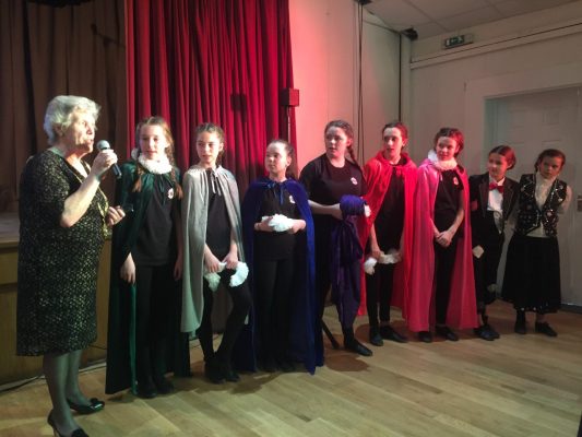 Mayor with microphone standing at end of a line of young people on stage