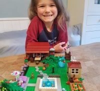 Young girl showing a garden made from Lego