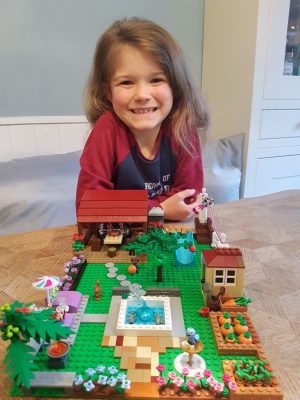 Young girl showing a garden made from Lego