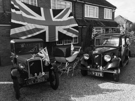 Black and white photo of vintage cars and old fashioned pram