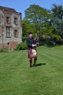 Scottish piper playing bagpipes in castle grounds