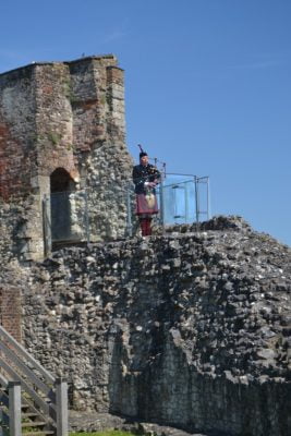 Scottish piper playing bagpipes on top of a castle