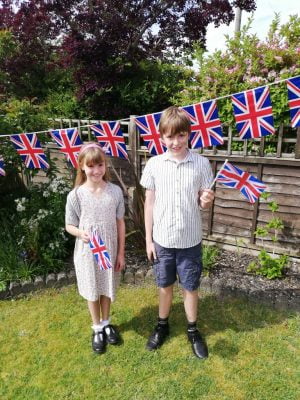 Girl and boy flying in a garden flying Union flags