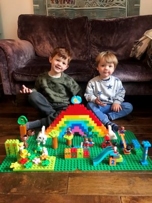 Two boys sitting on floor with Lego model garden