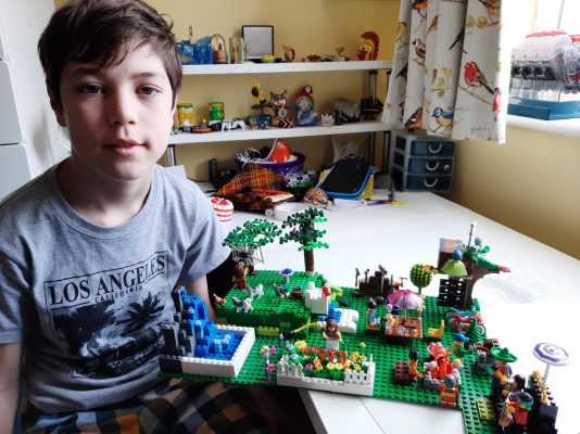 Young boy sitting at a desk with a lego model