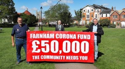 Three men holding banner advertising fundraising appeal