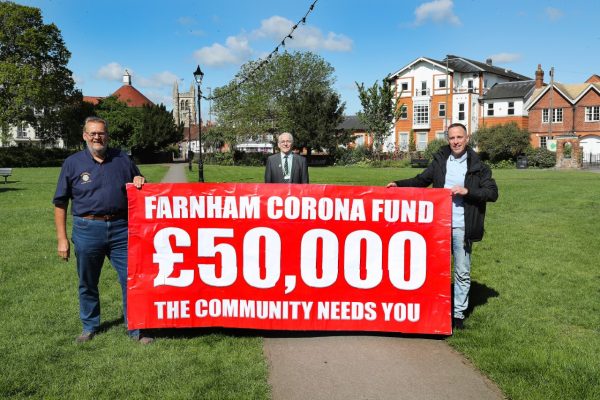 Three men holding banner advertising fundraising appeal