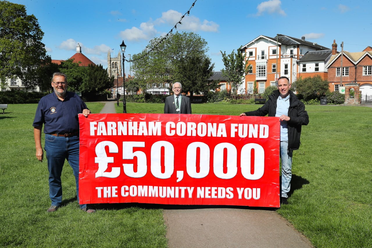 Three men holding banner advertising fundraising appeal