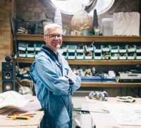 Smiling man wearing overalls standing in a workshop