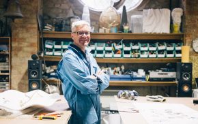 Smiling man wearing overalls standing in a workshop