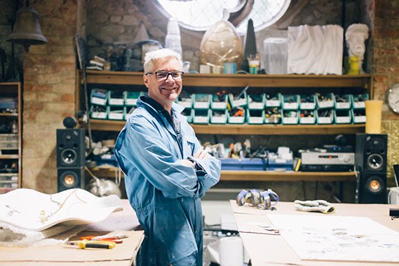 Smiling man wearing overalls standing in a workshop