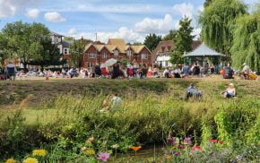 River and wildflowers in the foreground. Bandstand and people in the distance