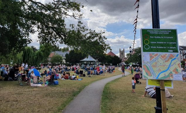 Footpath through park. People sitting on blankets, church tower in background
