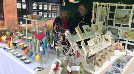 Two females standing behind a stall selling craft items.