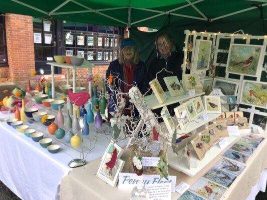 Two females standing behind a stall selling craft items.