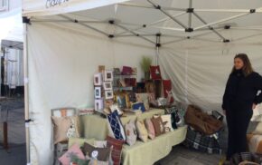 Market stall displaying cushions and craft items.