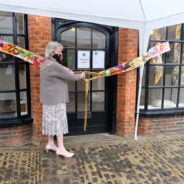 Female cuts a ribbon to mark the opening of a shop.