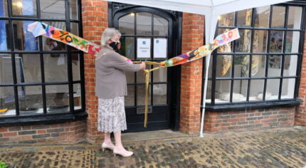 Female cuts a ribbon to mark the opening of a shop.