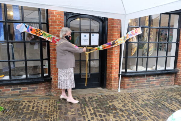 Female cuts a ribbon to mark the opening of a shop.
