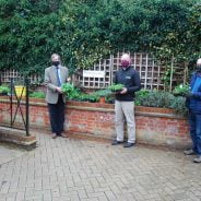 Four people standing in front of flower bed