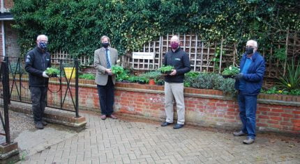 Four people standing in front of flower bed