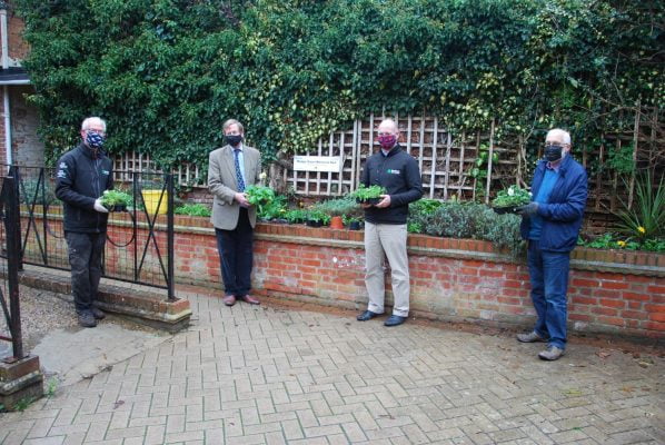 Four people standing in front of flower bed