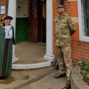 Mayor and solider standing in front of a red brick building.