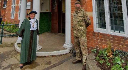 Mayor and solider standing in front of a red brick building.