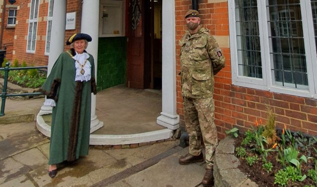 Mayor and solider standing in front of a red brick building.