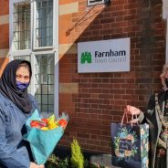 Female holding flowers and presenting a gift bag to the Mayor.