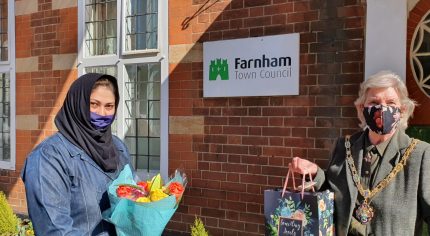 Female holding flowers and presenting a gift bag to the Mayor.