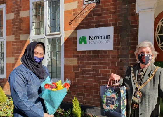 Female holding flowers and presenting a gift bag to the Mayor.