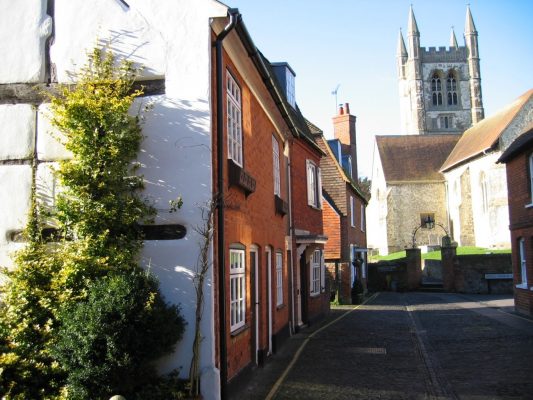 Row of pretty cottages with church with tower in the background.