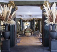 View through a doorway at a seating area. Door flanked by large vases of grass.