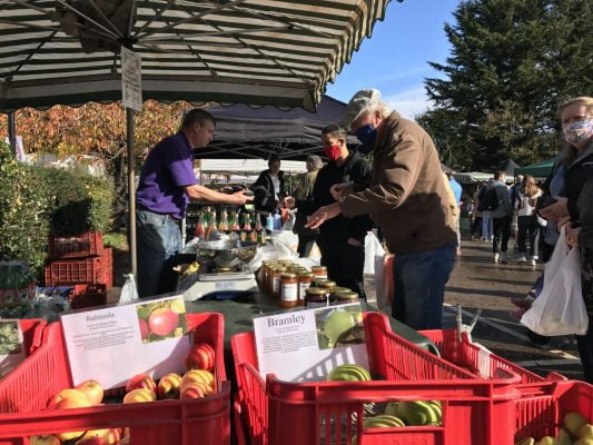 People buying apples at a market stall