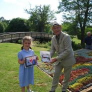 Young girl holds a drawing and receiving a prize from the Mayor.