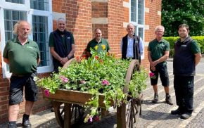 Six members of the Council's Outside workforce standing around the freshly planted hop cart outside the Council offices