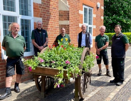 Six members of the Council's Outside workforce standing around the freshly planted hop cart outside the Council offices