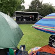 Umbrellas in foreground and stage with band performing in background.