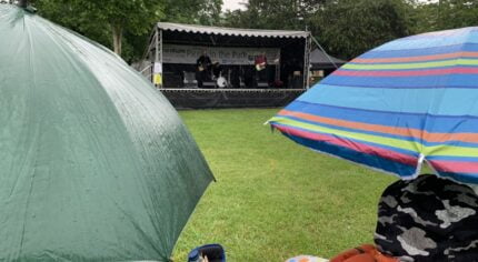 Umbrellas in foreground and stage with band performing in background.