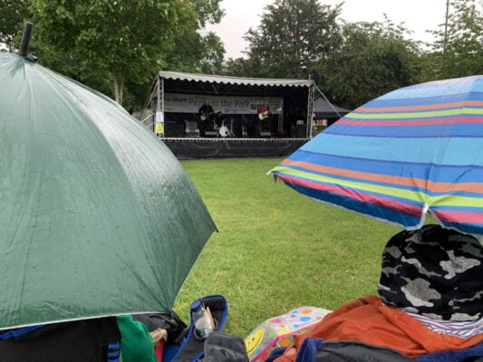 Umbrellas in foreground and stage with band performing in background.