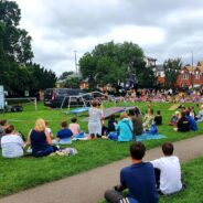 Crowd of people sitting on grass watching a stunt bike rider