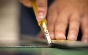 Close up of a hand cutting glass.