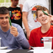 Two young males each holding a green chilli