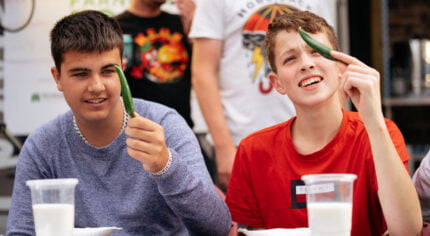 Two young males each holding a green chilli