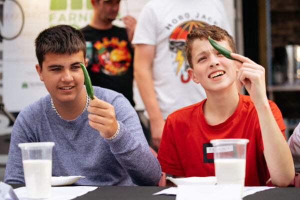 Two young males each holding a green chilli
