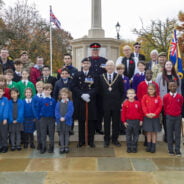 Group of school children with Mayor and service personnel at war memorial