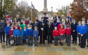 Group of school children with Mayor and service personnel at war memorial