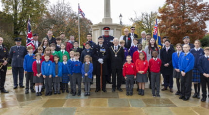 Group of school children with Mayor and service personnel at war memorial